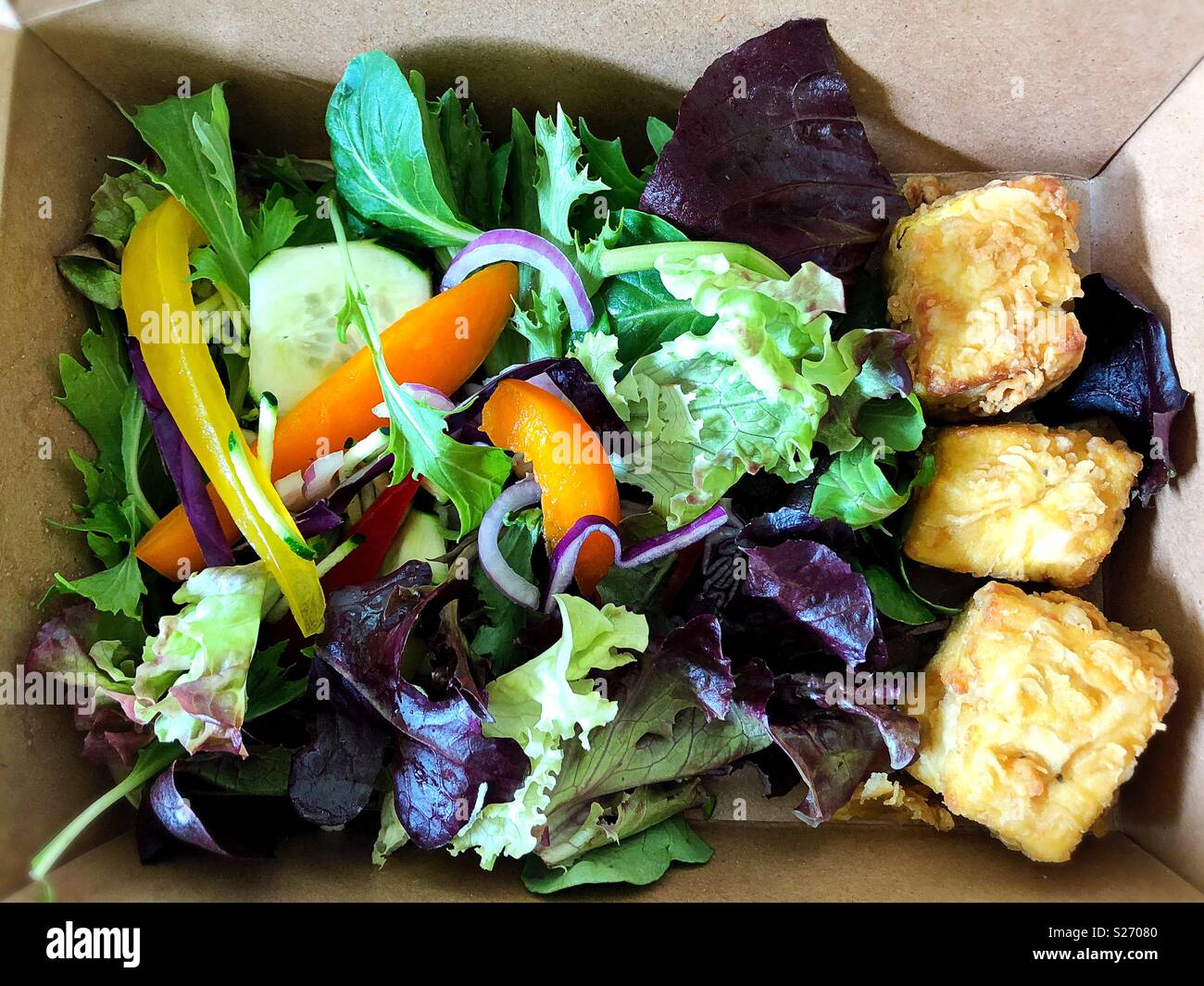 A nutritious lunch of salad and fried tofu, from above, in a carry out container. Stock Photo