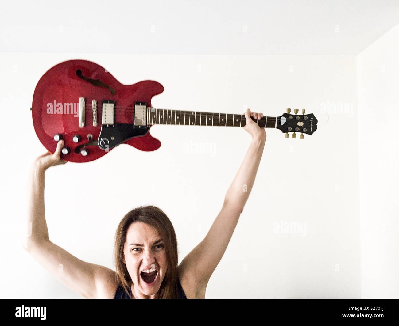 woman holding an electric guitar and screaming - Smartphone Captured Stock Image