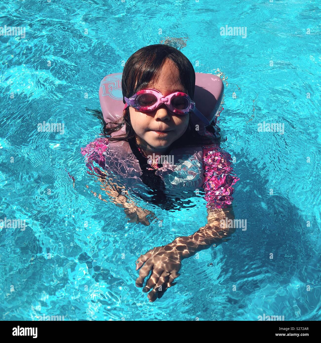 Portrait of 5 year old girl wearing a life jacket and goggles in a swimming pool Stock Photo Alamy