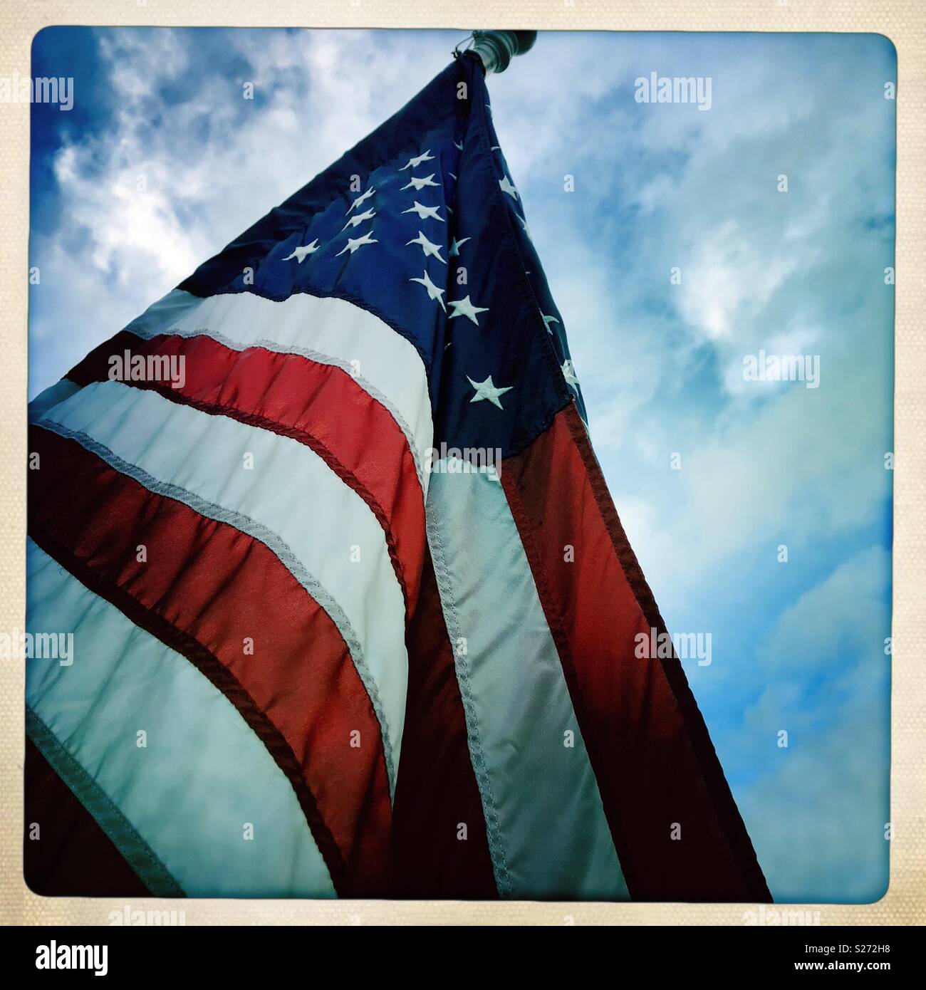 American Flag against partly cloudy sky Stock Photo