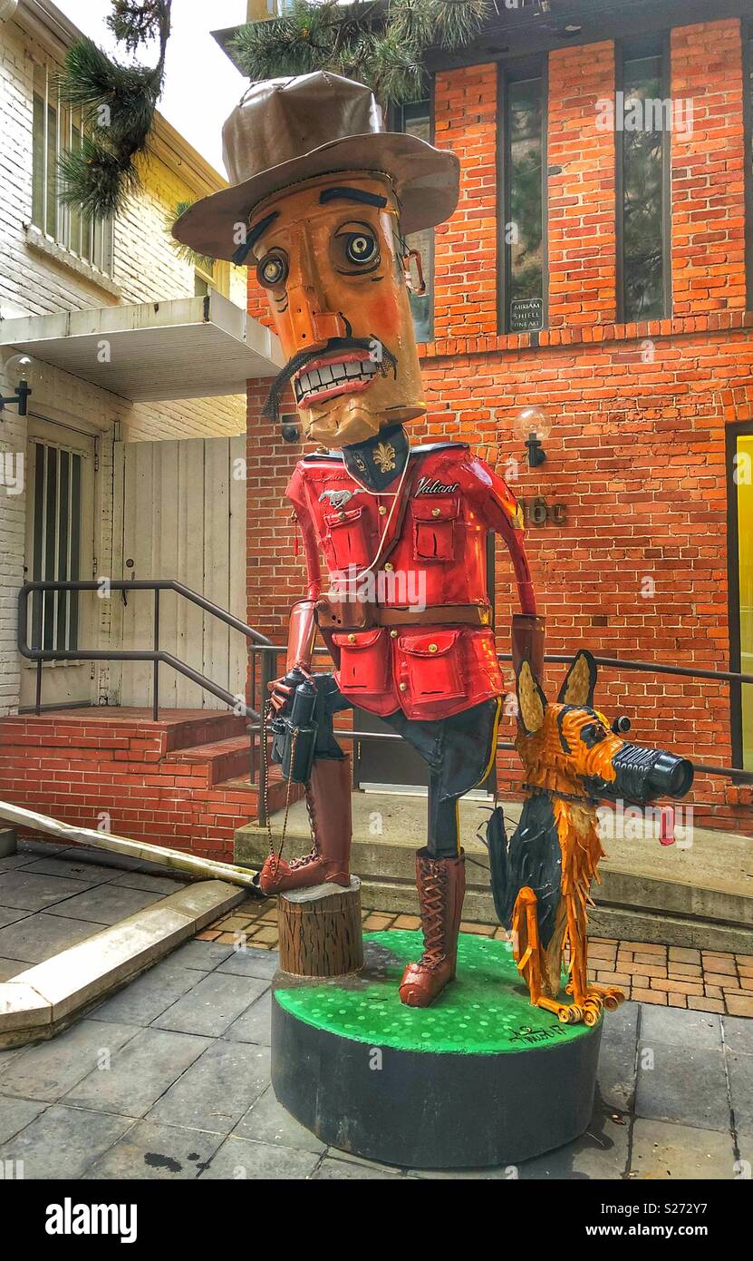 A whimsical sculpture of a Canadian Mounted Police with his dog. - Smartphone Captured Stock Image