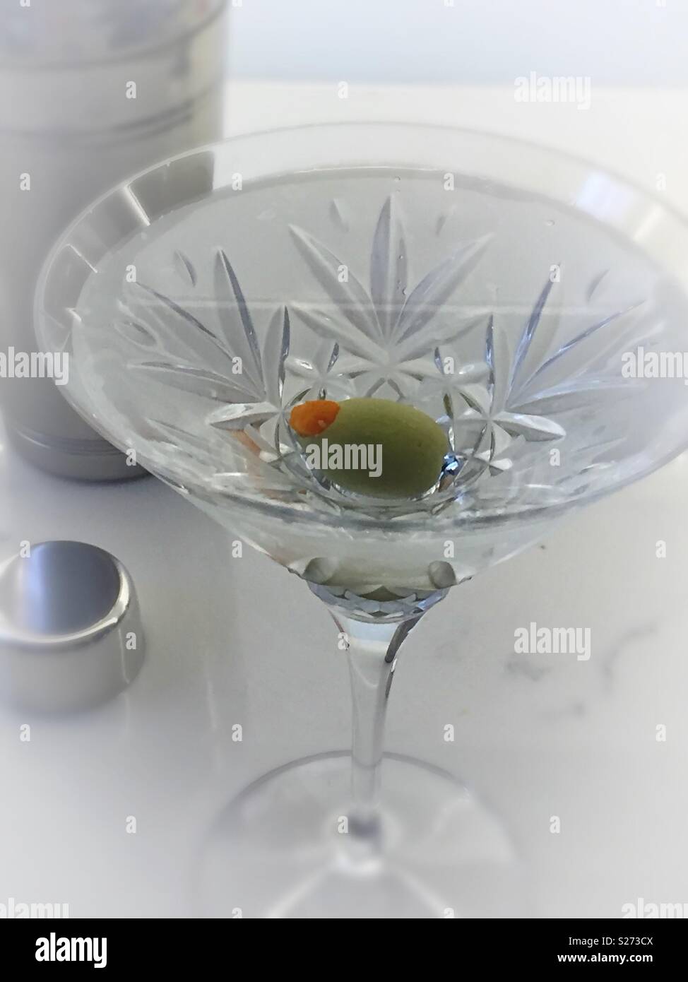 The classic dry gin martini next to a Cocktail shaker, served in a