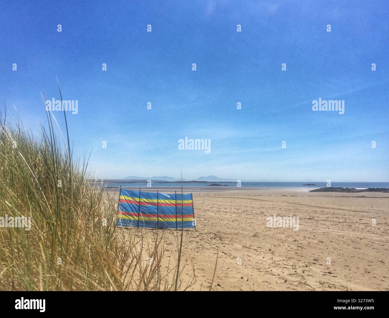 One stripy windbreaker on a beach, Rhosneigr, Anglesey, North Wales, UK - Smartphone Captured Stock Image