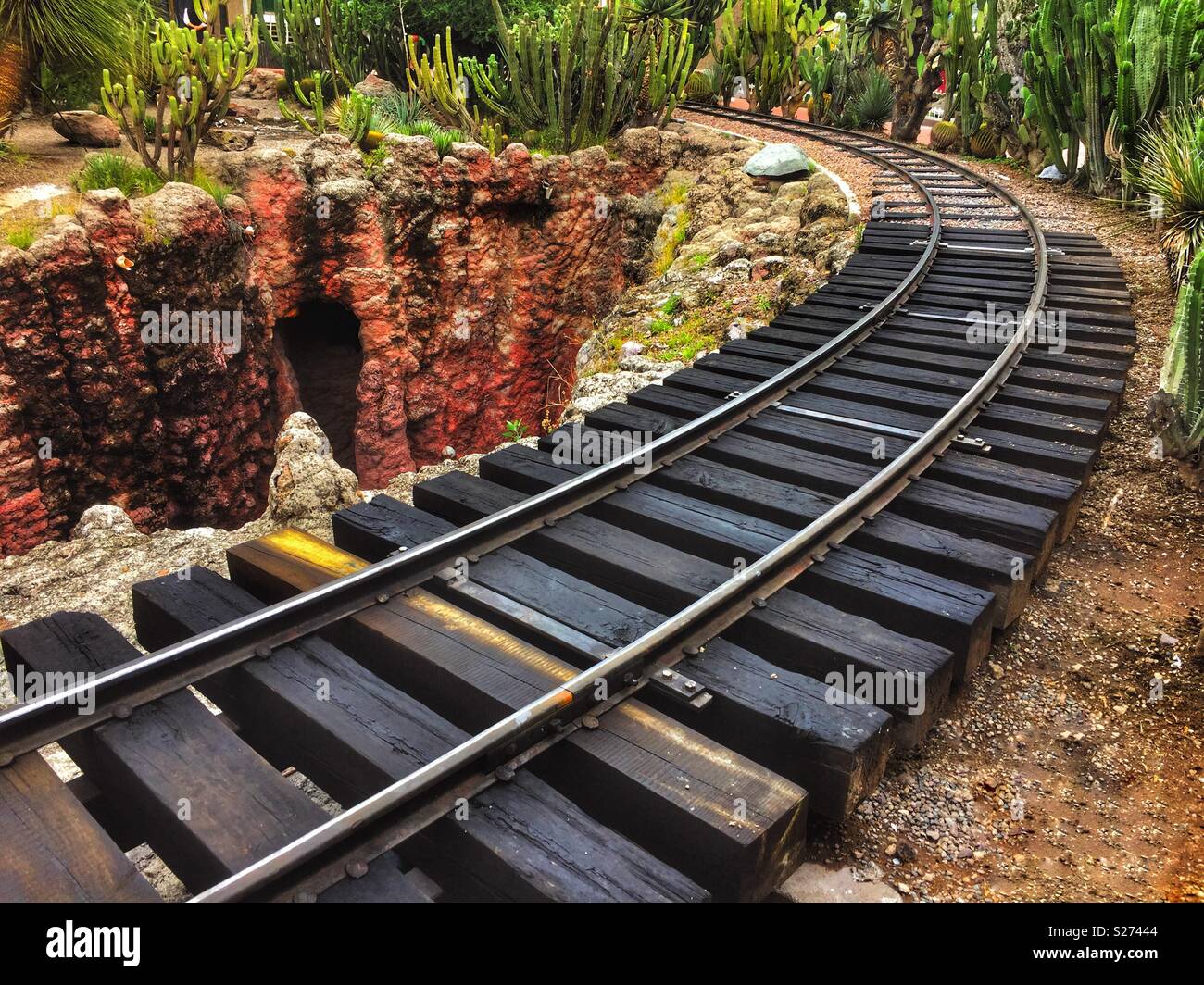 curved train track, timbers, rails, background vegetation in national park Stock Photo