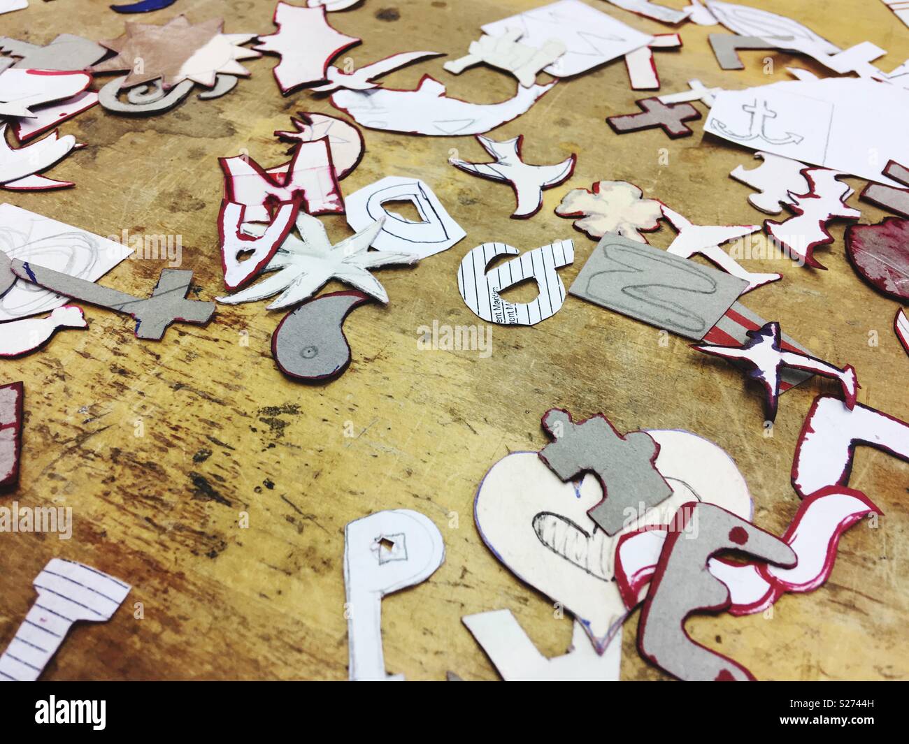 Paper shapes and forms used as templates for goldsmith or jeweller apprentices on a wooden surface Stock Photo