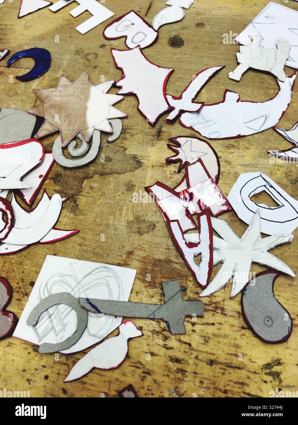 Paper shapes and forms used as templates for goldsmith or jeweller apprentices on a wooden surface - Smartphone Captured Stock Image