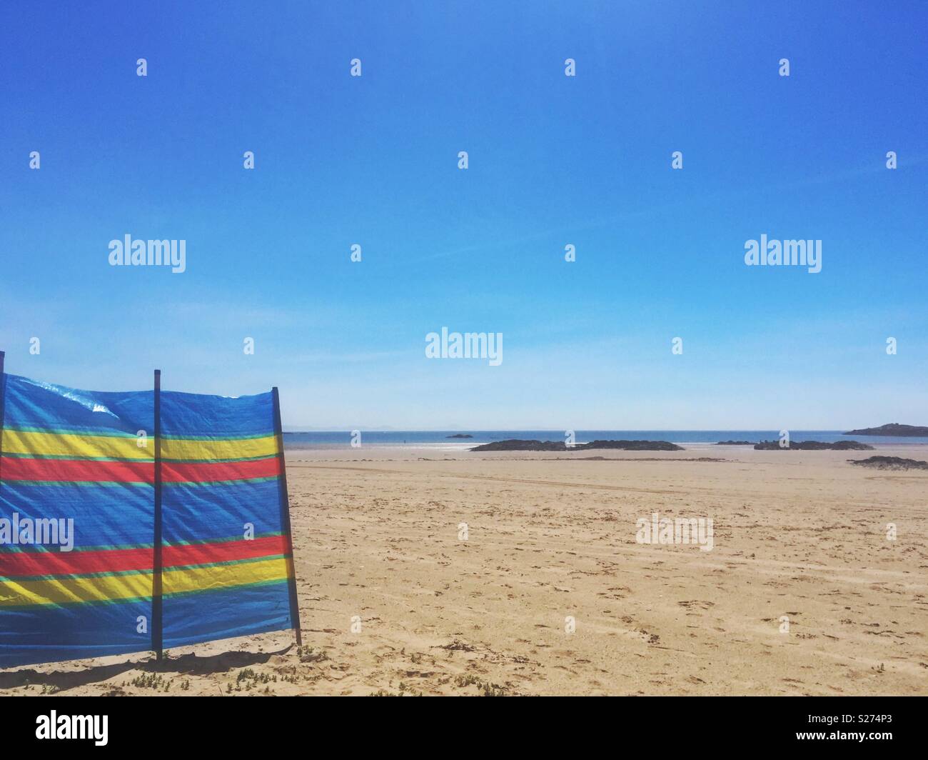 Striped windbreaker on empty beach in summer, Anglesey, North Wales, UK - Smartphone Captured Stock Image