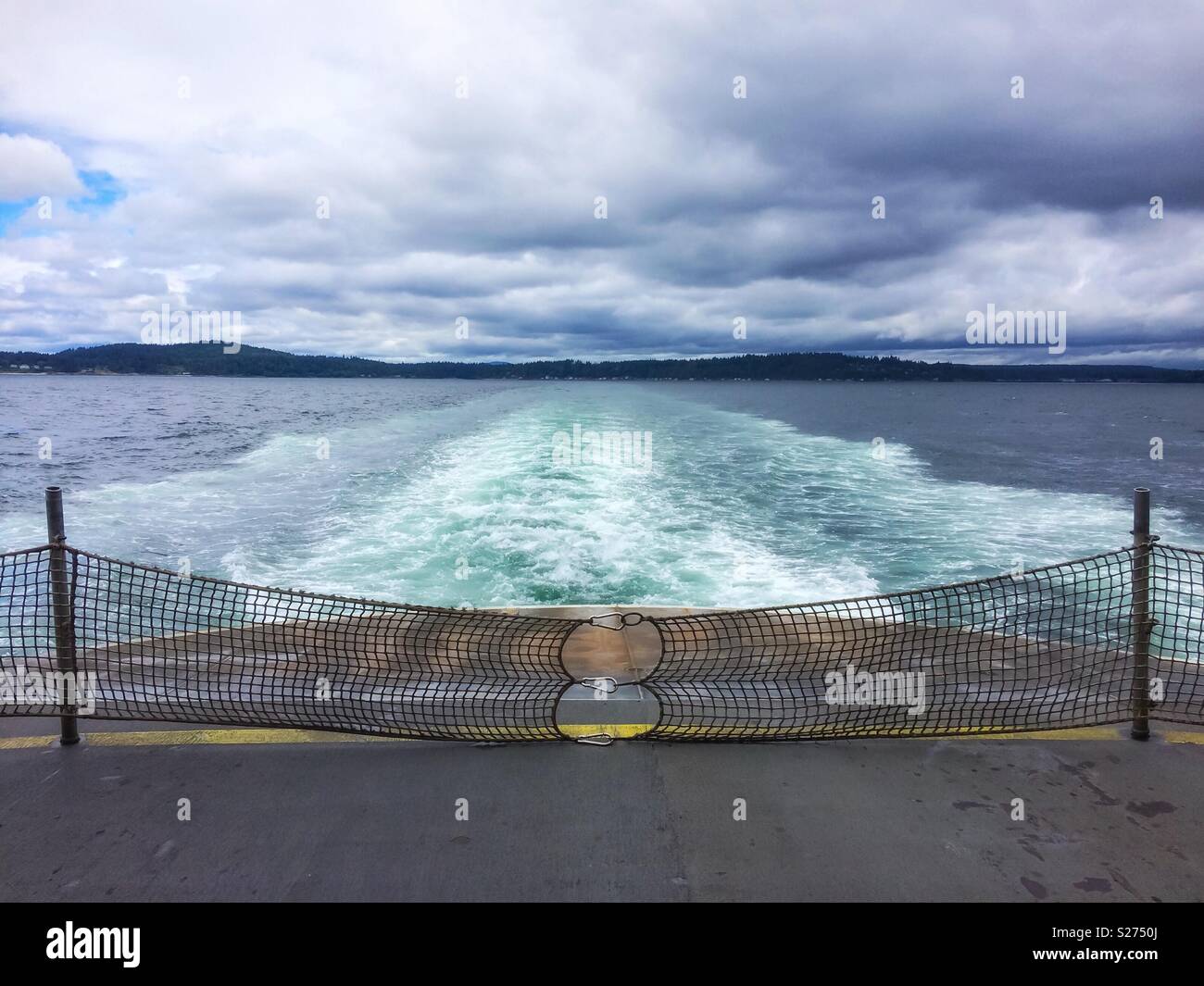 Ferry boat wake with Bainbridge Island as the horizon line on a cloudy day, Puget Sound, Washington State, USA. - Smartphone Captured Stock Image