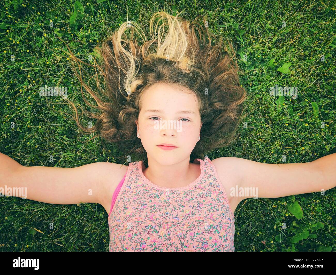 10 11 12 year old girls 11 year old girl laying in the grass with arms out and serious expression  on her face Stock Photo - Alamy