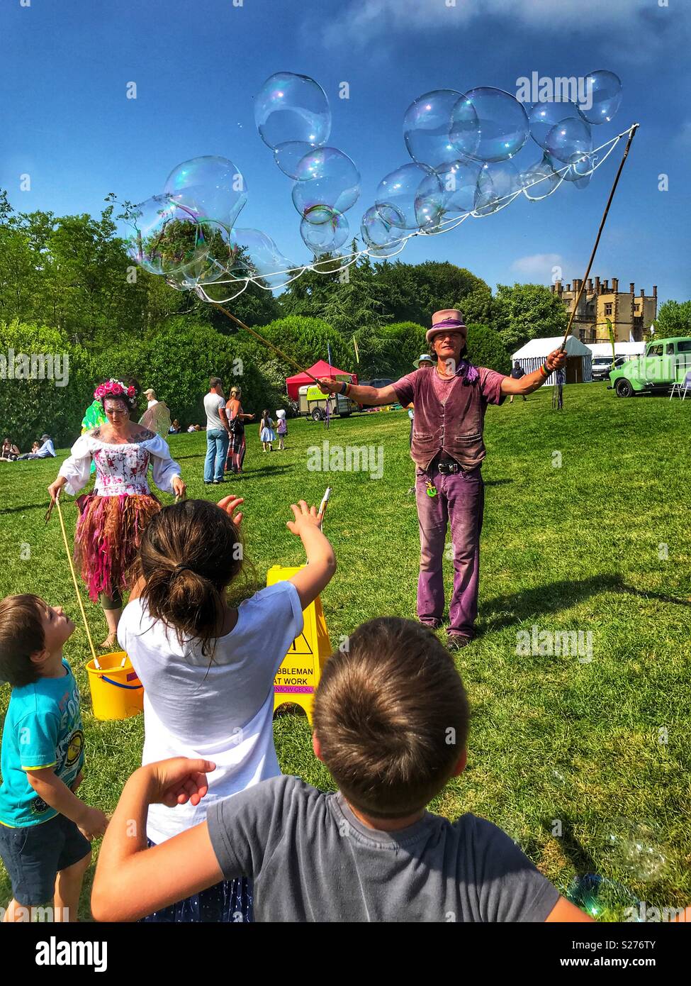 Man creating giant soap bubbles, entertaining children at Sherborne Castle Country Fair, Sherborne, Dorset, England - Smartphone Captured Stock Image