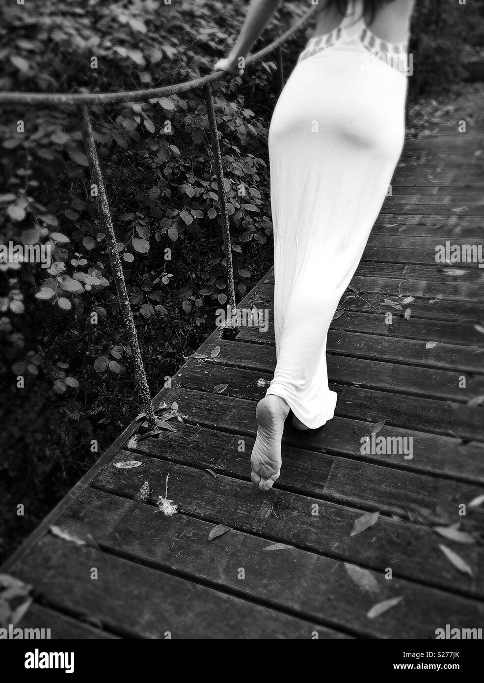 A young woman walking across a bridge. Stock Photo