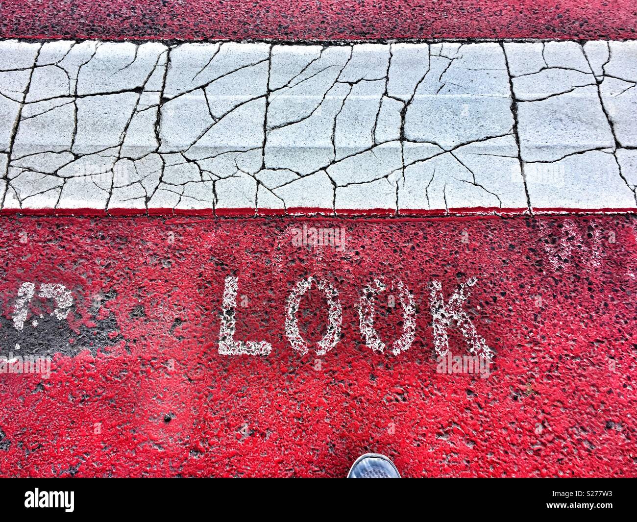Look. Red and white Painted crosswalk on road with tip of running shoe - Smartphone Captured Stock Image
