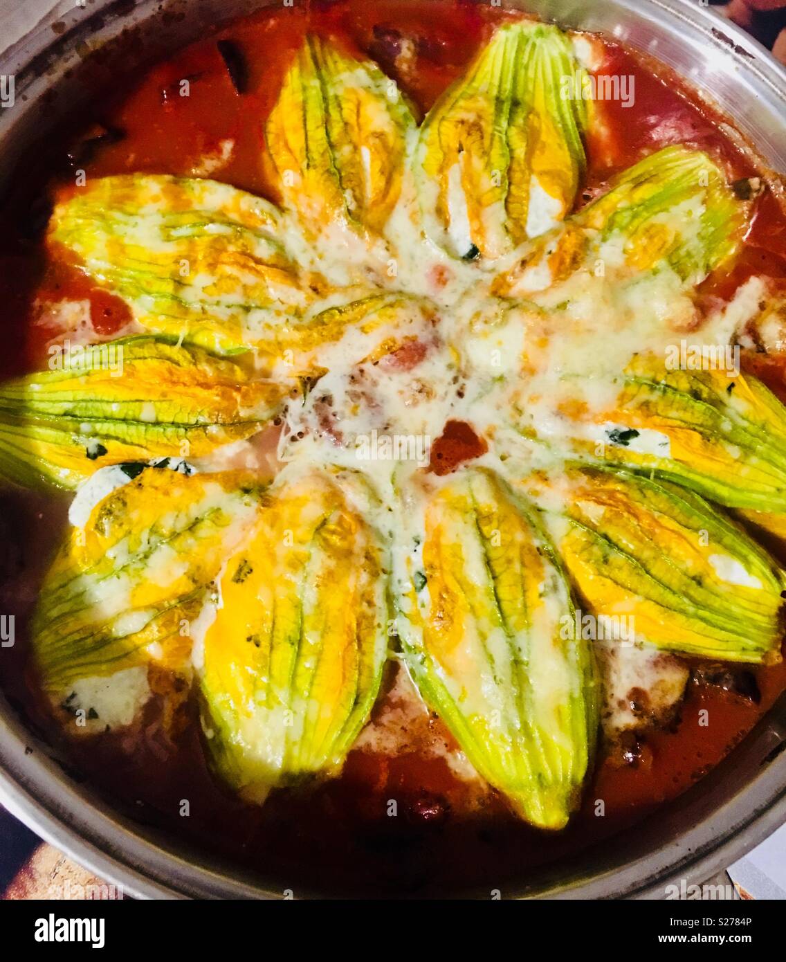 Traditional Roman cuisine.Zucchini flowers stuffed with mozzarella and Ricotta cheese cooked in tomato sauce. Stock Photo