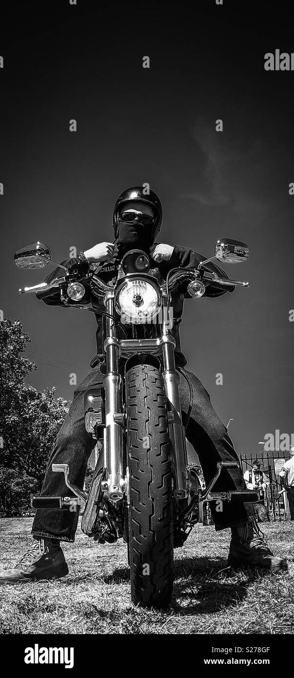 Black and white shot of a chopper motorcycle rider fastening his helmet Stock Photo
