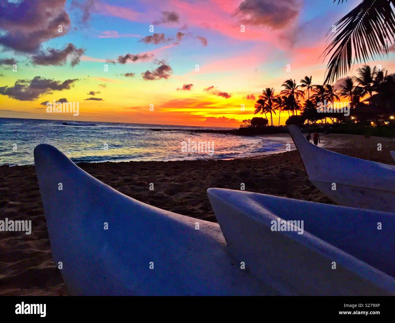 Tropical island beach paradise sunset, lovers walking hand-in-hand, outrigger canoes, palm trees - Smartphone Captured Stock Image