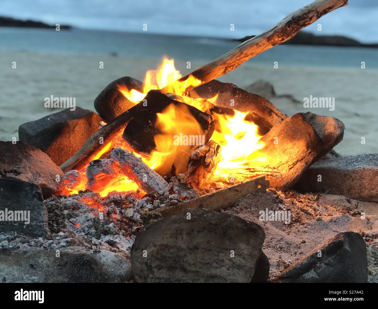 Close up of beach campfire on white sand beach in Scottish Highlands on a light June evening - Smartphone Captured Stock Image