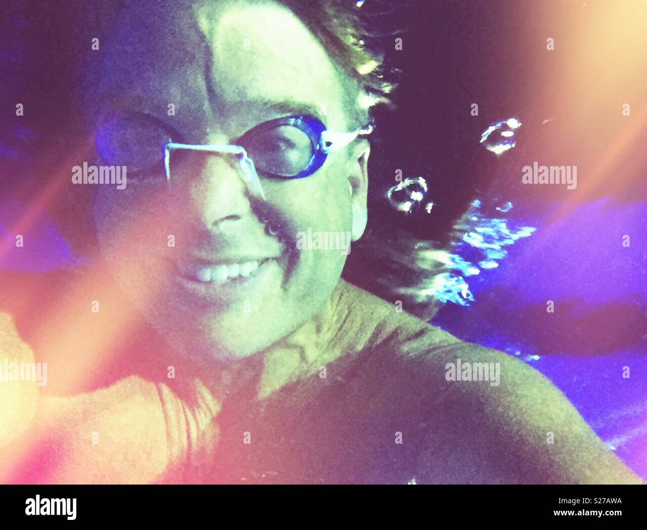 Beams of sunlight streaming through the water onto submerged swimmer, bubbles gushing from behind - Smartphone Captured Stock Image