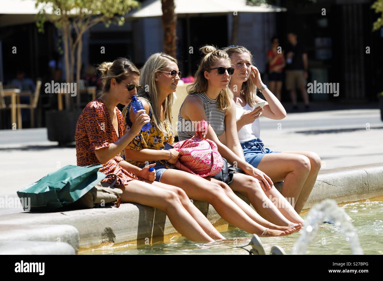a group of tourists cool off in a fountain in Valencia on a day where thermometers reach 40 degrees - Smartphone Captured Stock Image