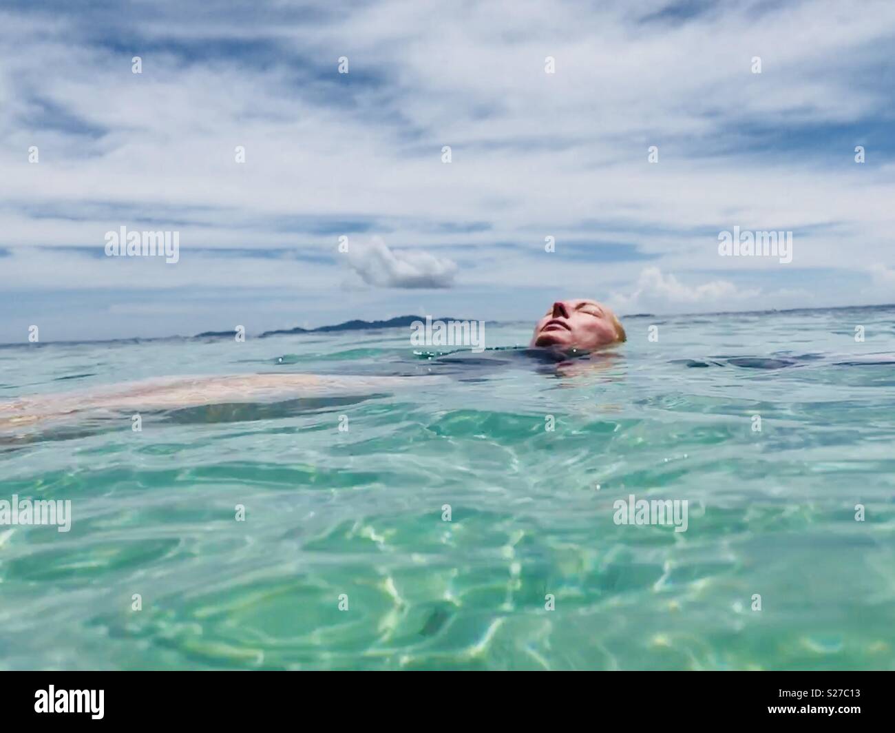 A young women floating in the ocean. Tavarua Island resort, Fiji. Stock Photo