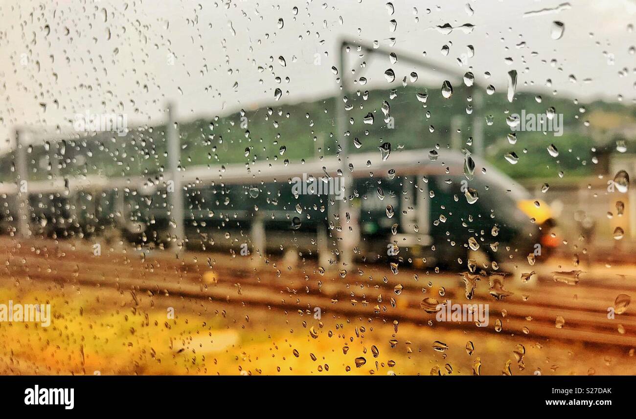 Raindrops on the window of an express train as it passes another train Stock Photo