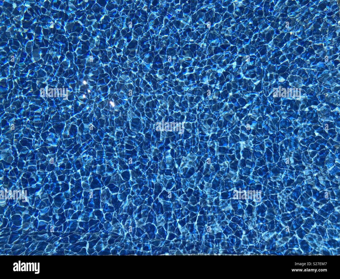 Light reflecting on water in an outdoor swimming pool Stock Photo