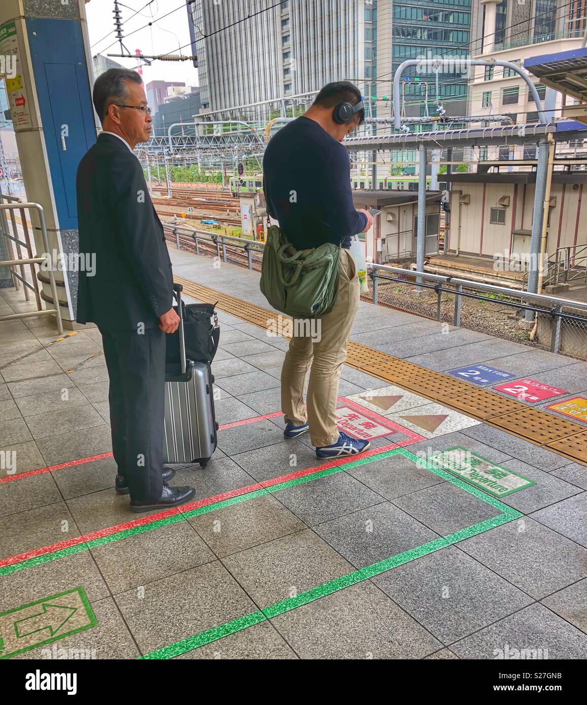 Two Japanese men waiting in line on a train platform in Tokyo. - Smartphone Captured Stock Image