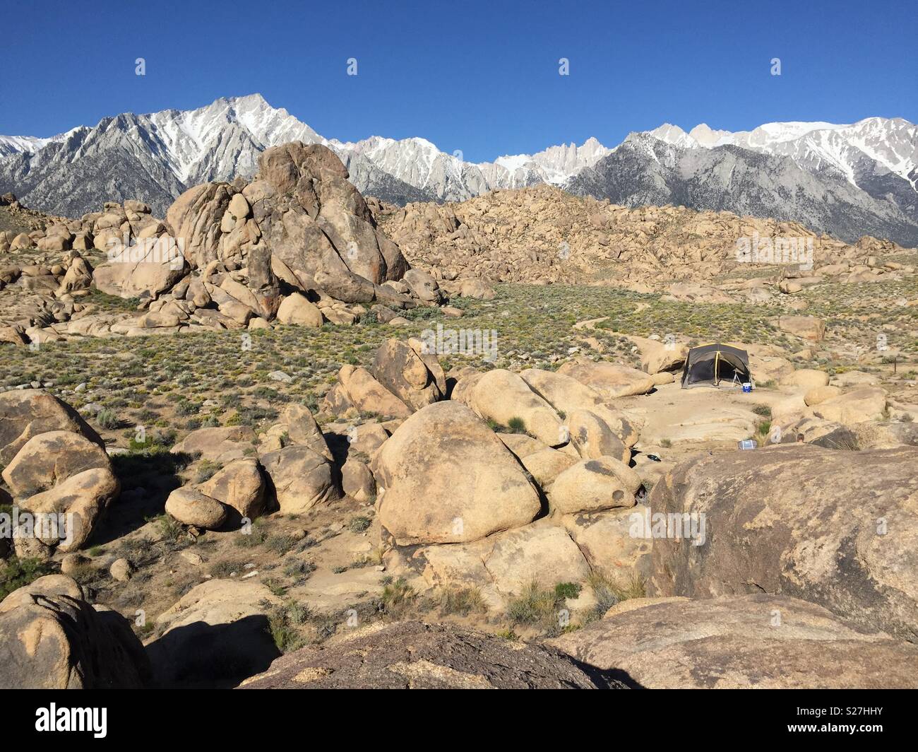 A campsite in rocky terrain with mountains in the background. Stock Photo