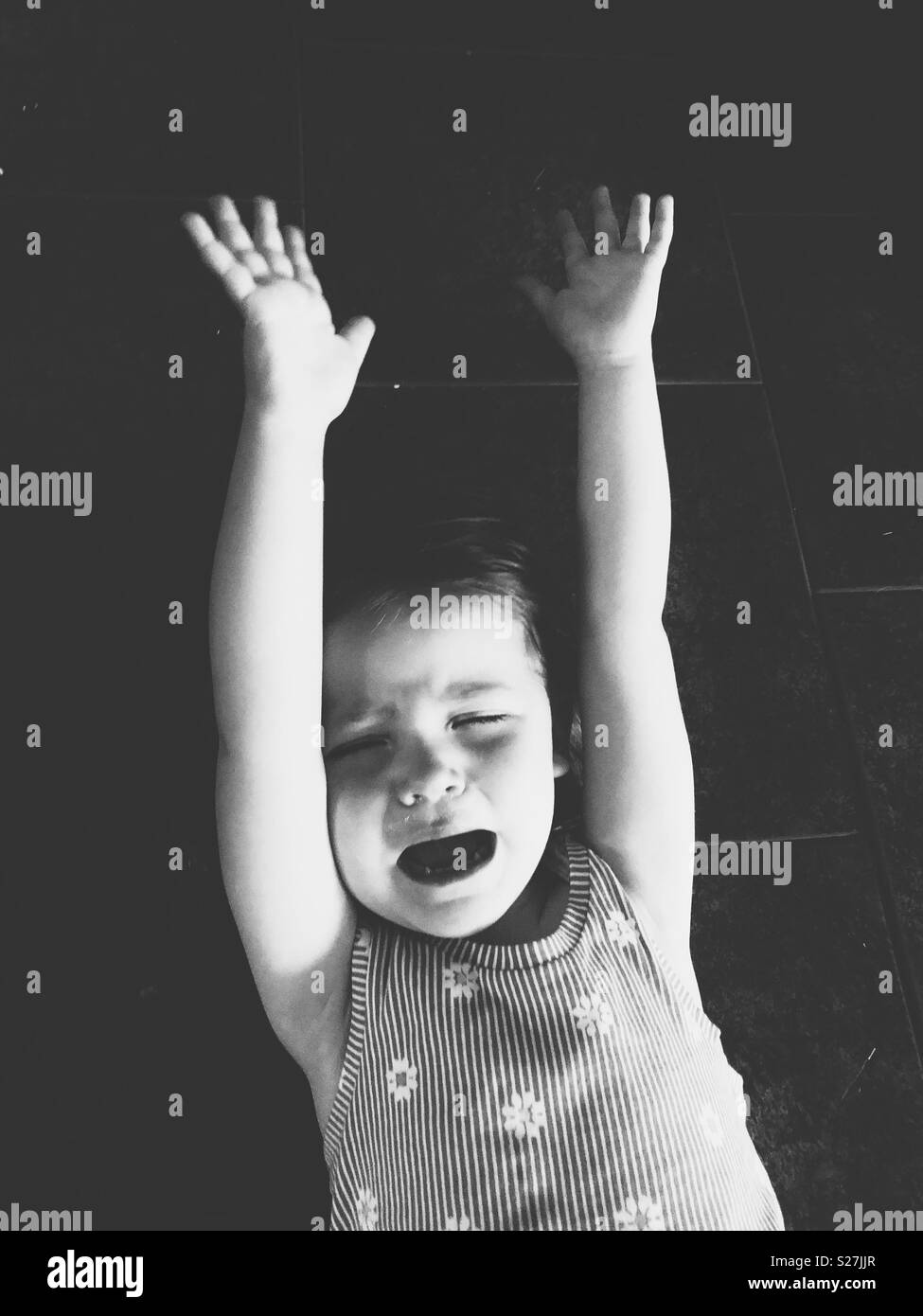B&W image of toddler girl having a temper tantrum on a floor Stock Photo