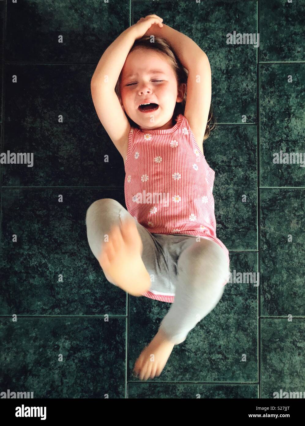 Toddler girl laying on floor kicking while having a temper tantrum Stock Photo