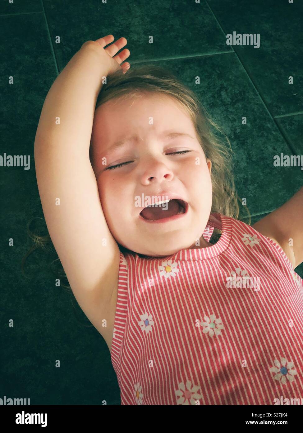 Toddler girl having a temper tantrum on tile floor Stock Photo