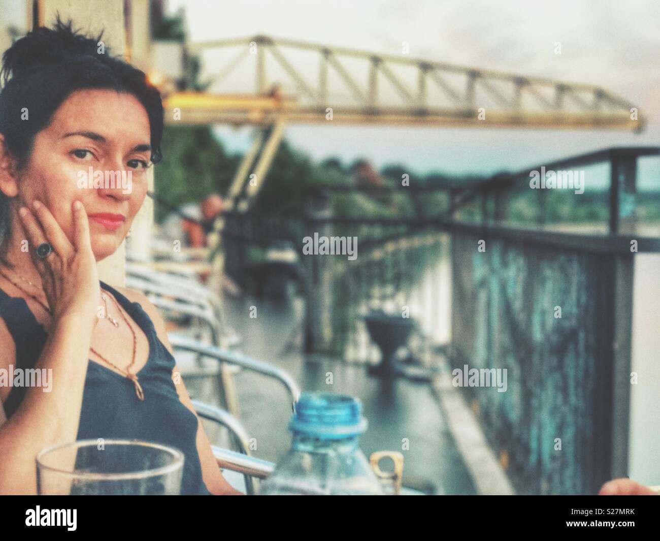 Woman in a outdoors terrace looking at the camera at sunset - Smartphone Captured Stock Image