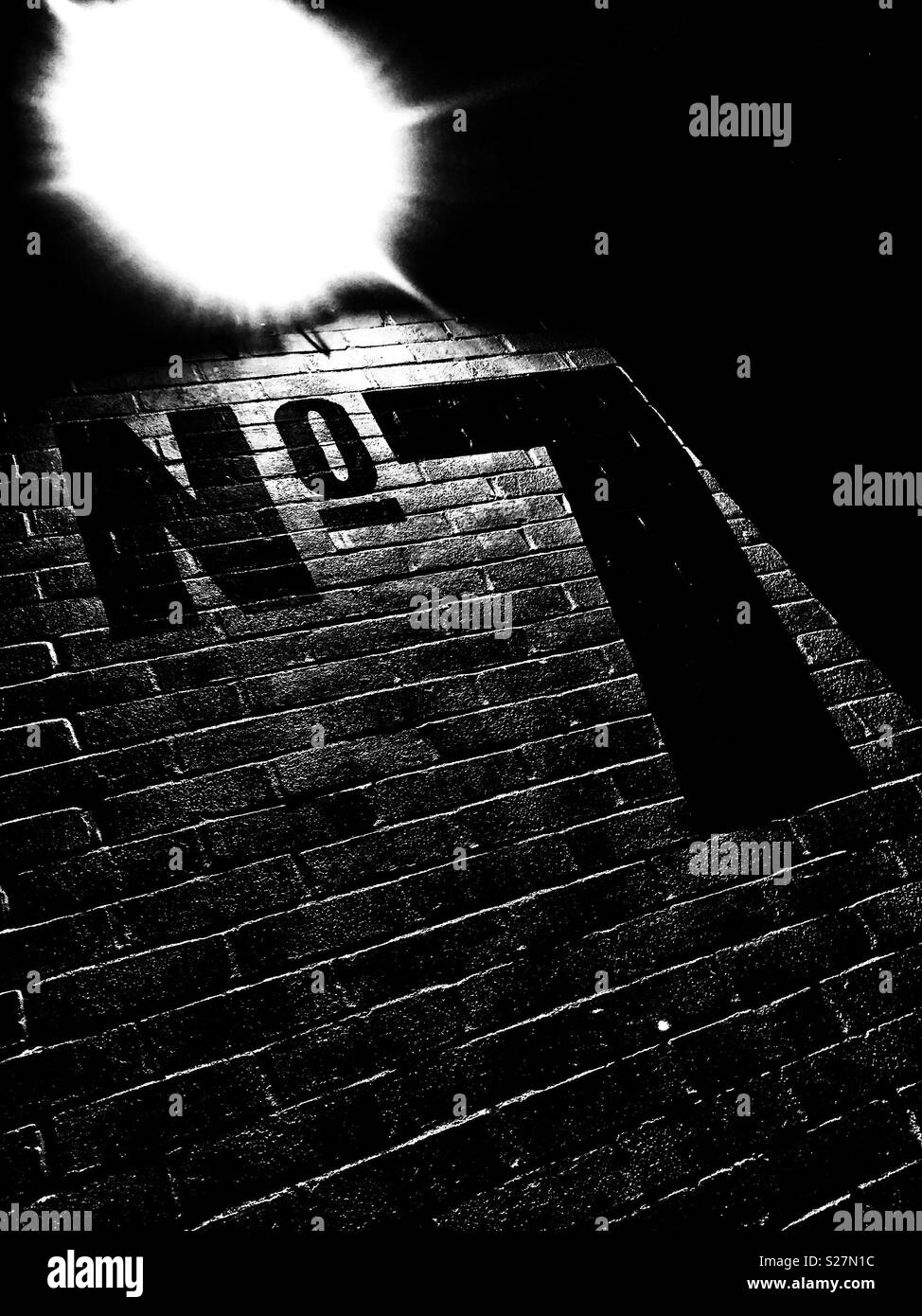 Large black Number 7 painted on the white brick wall of an industrial unit. Stock Photo