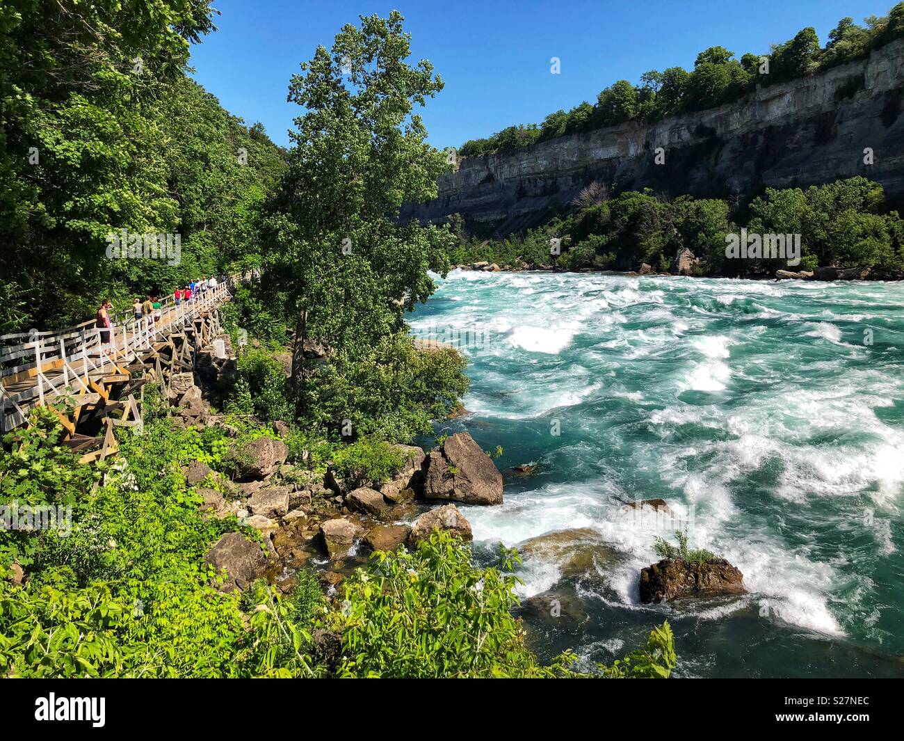 Tourists walk along the white water rapids of the Niagara River in Niagara Falls, Ontario, Canada Stock Photo