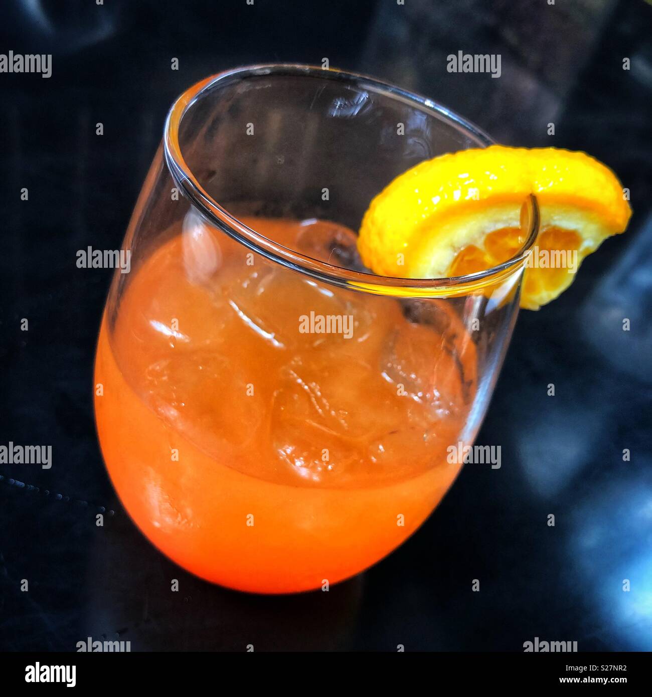 An orange mixed drink in a cocktail glass on a black background Stock Photo