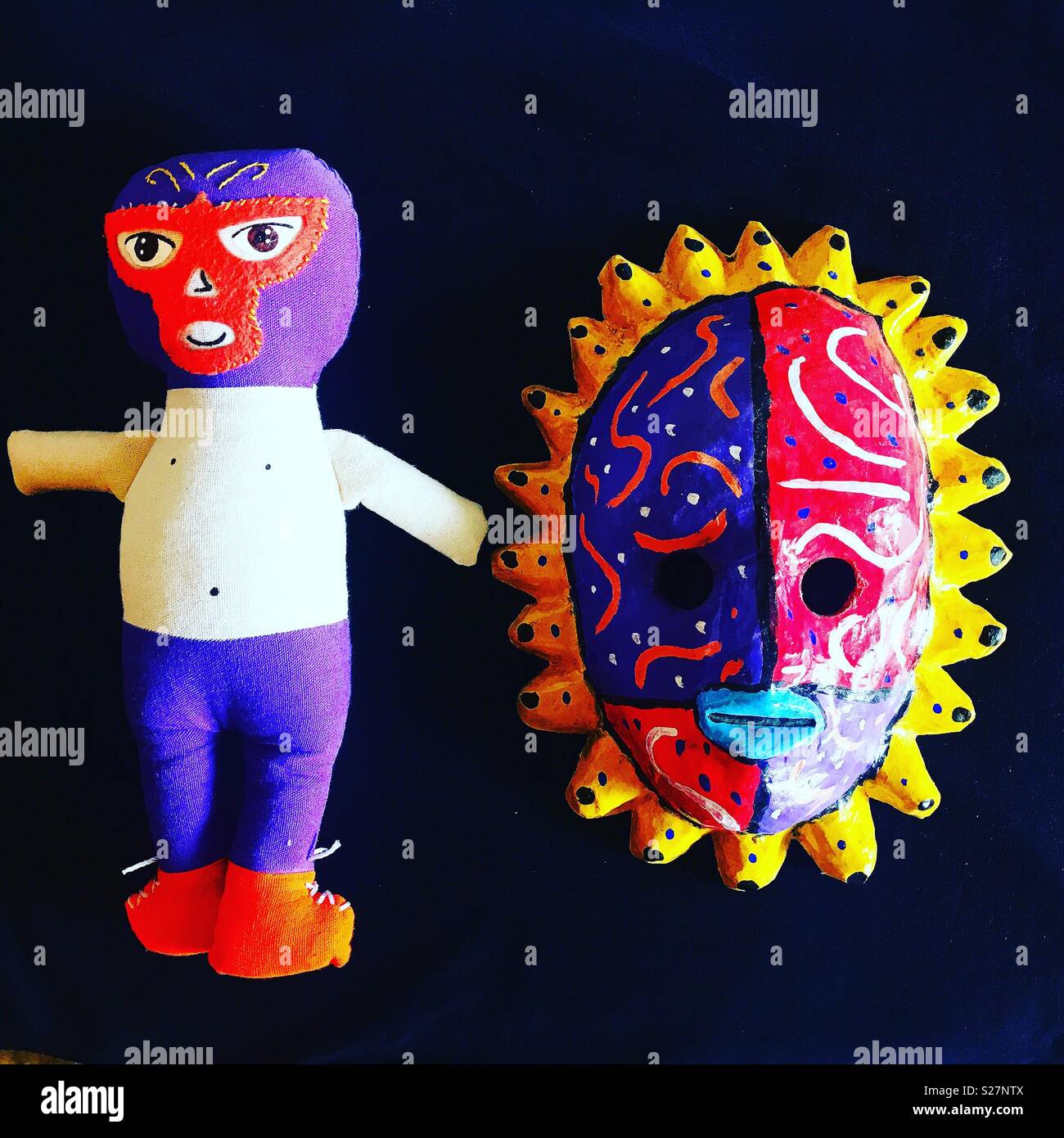 A toy dressed as a Mexican wrestler and a sun mask decorate Taller Tlamaxcalli in Colonia Roma, Mexico City, Mexico - Smartphone Captured Stock Image