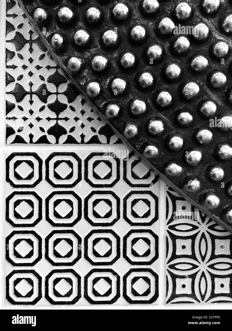 A circular studded frame against three different geometric patterned tiles Stock Photo