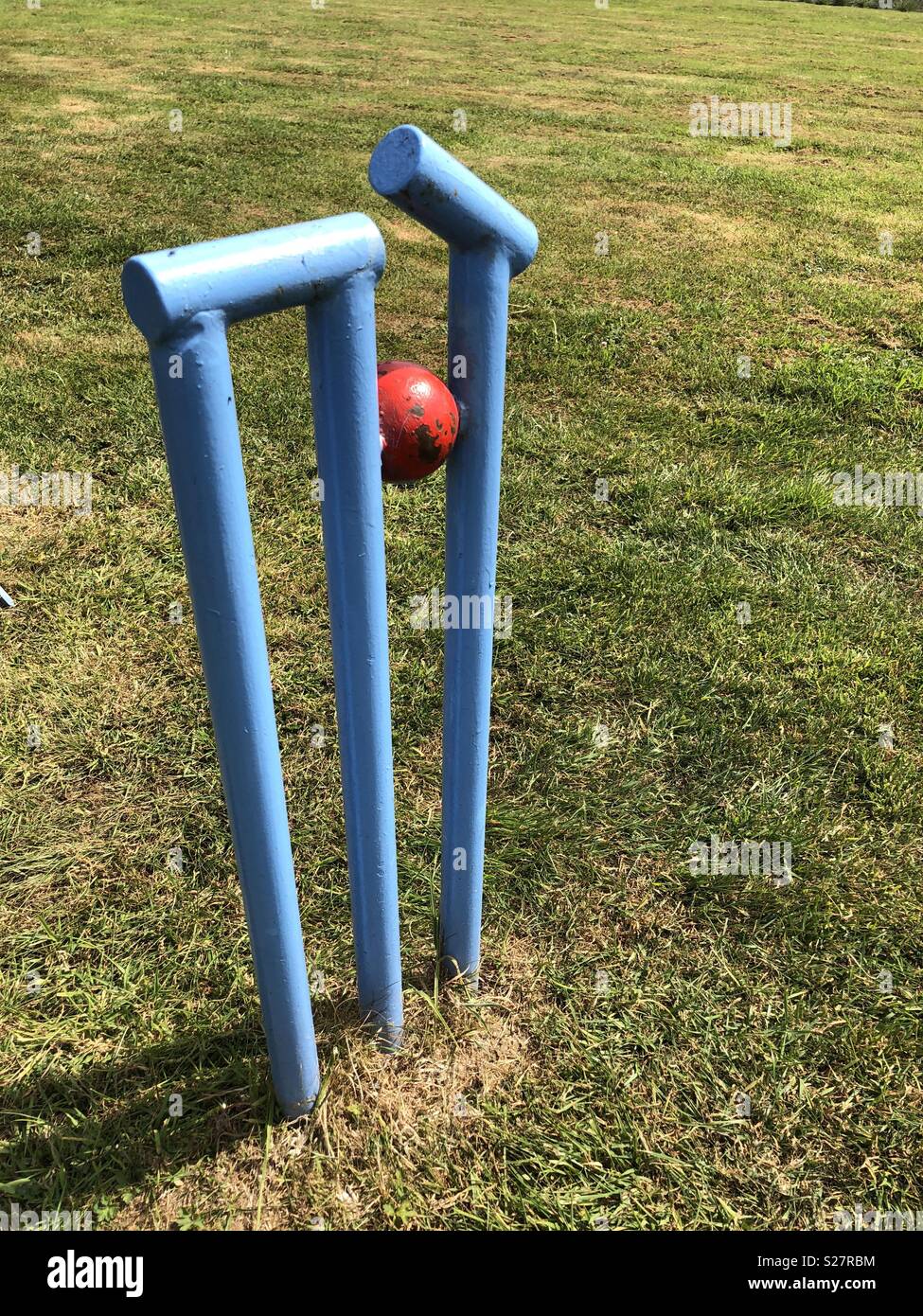 Howzat? - Sculpture of cricket wicket at the moment the red ball hits the wicket and knocks off the bails Stock Photo