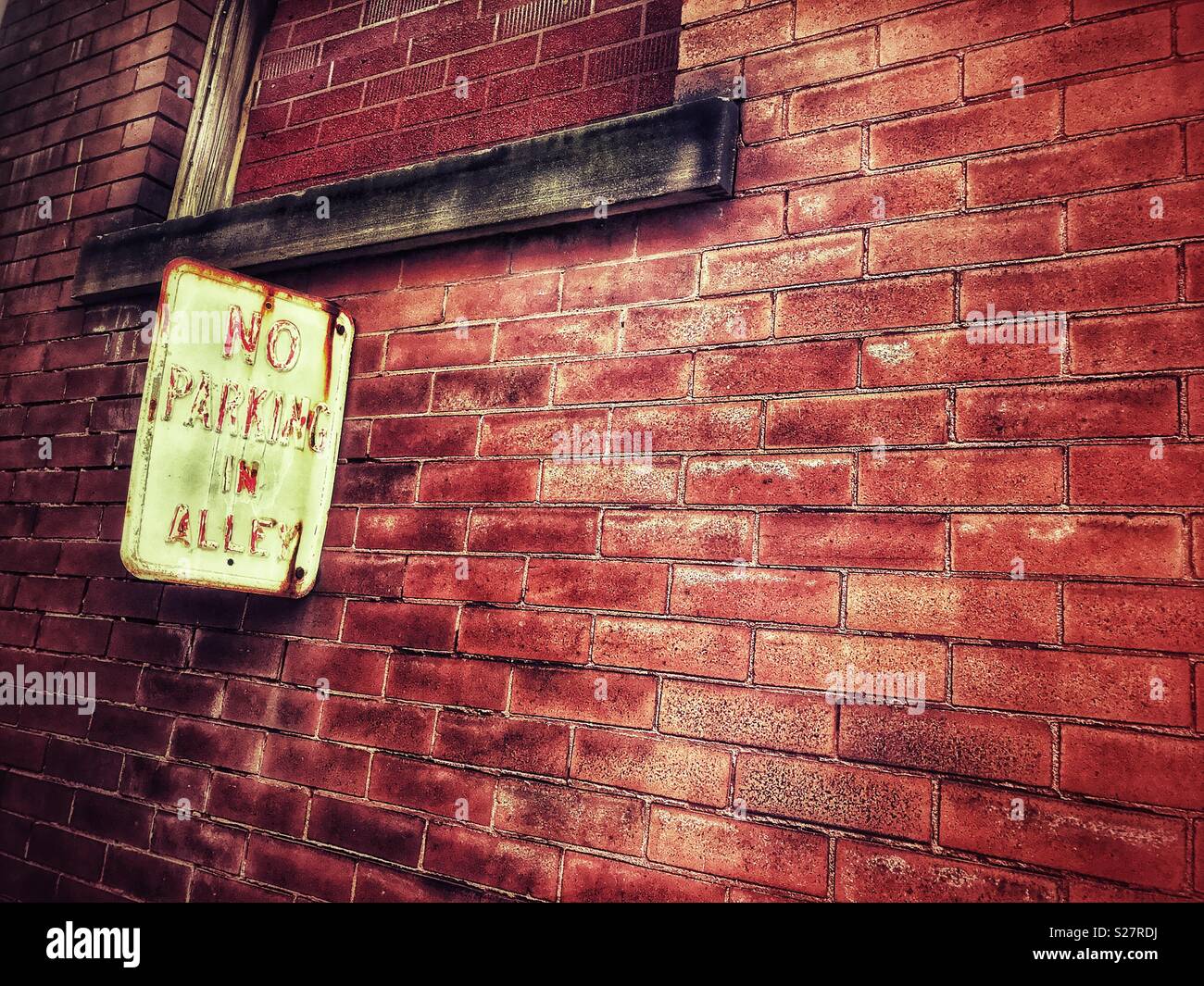 No Parking in Alley sign on weathered brick wall - Smartphone Captured Stock Image
