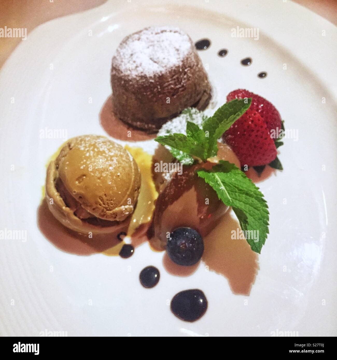 Liquid centre dark chocolate flan with espresso ice cream and strawberries, a dessert at Spasso Italian bar and restaurant, Tsim Sha Tsui, Kowloon, Hong Kong - Smartphone Captured Stock Image