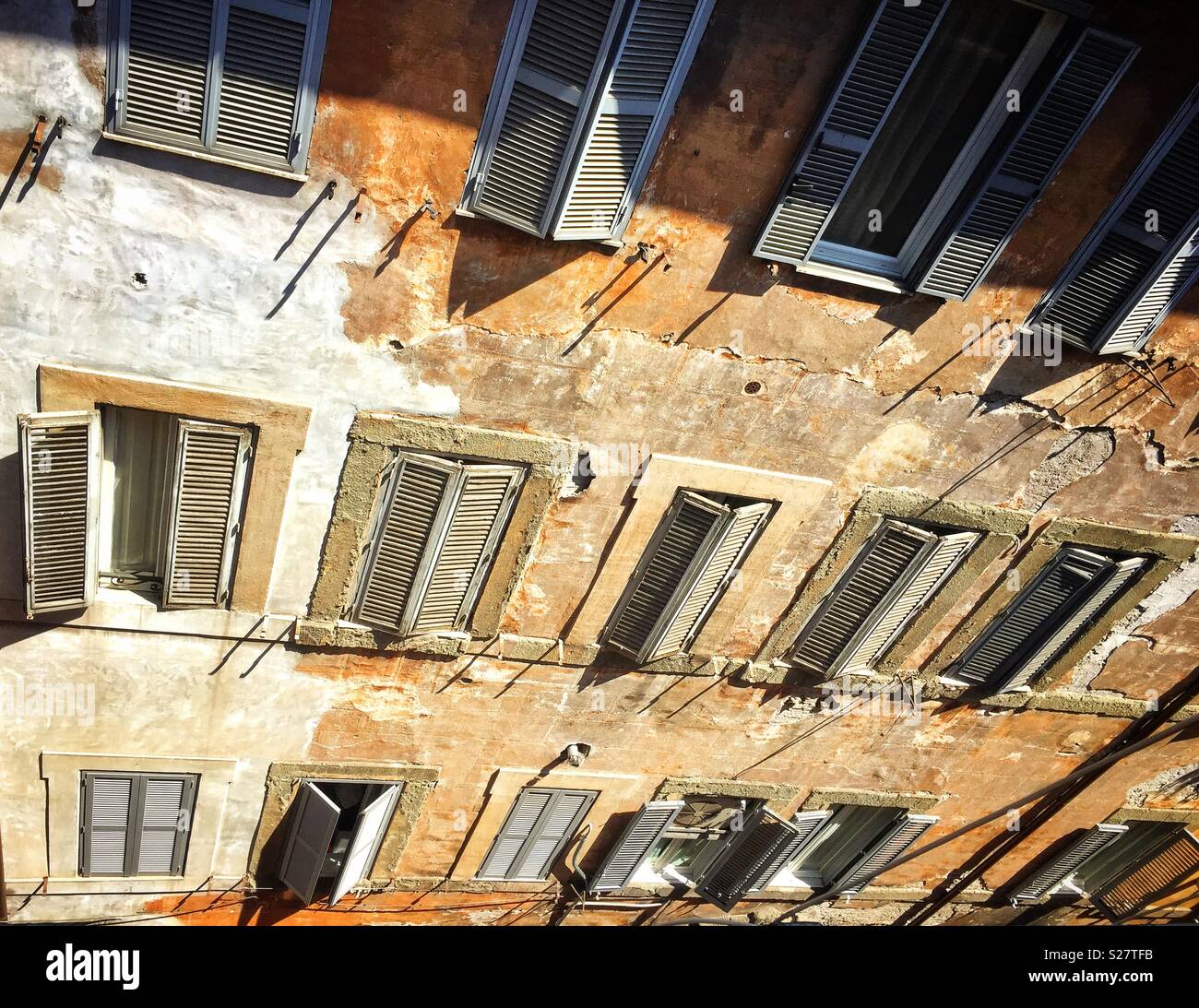 Facade of an ancient residential building with patterned windows and shutters - Smartphone Captured Stock Image