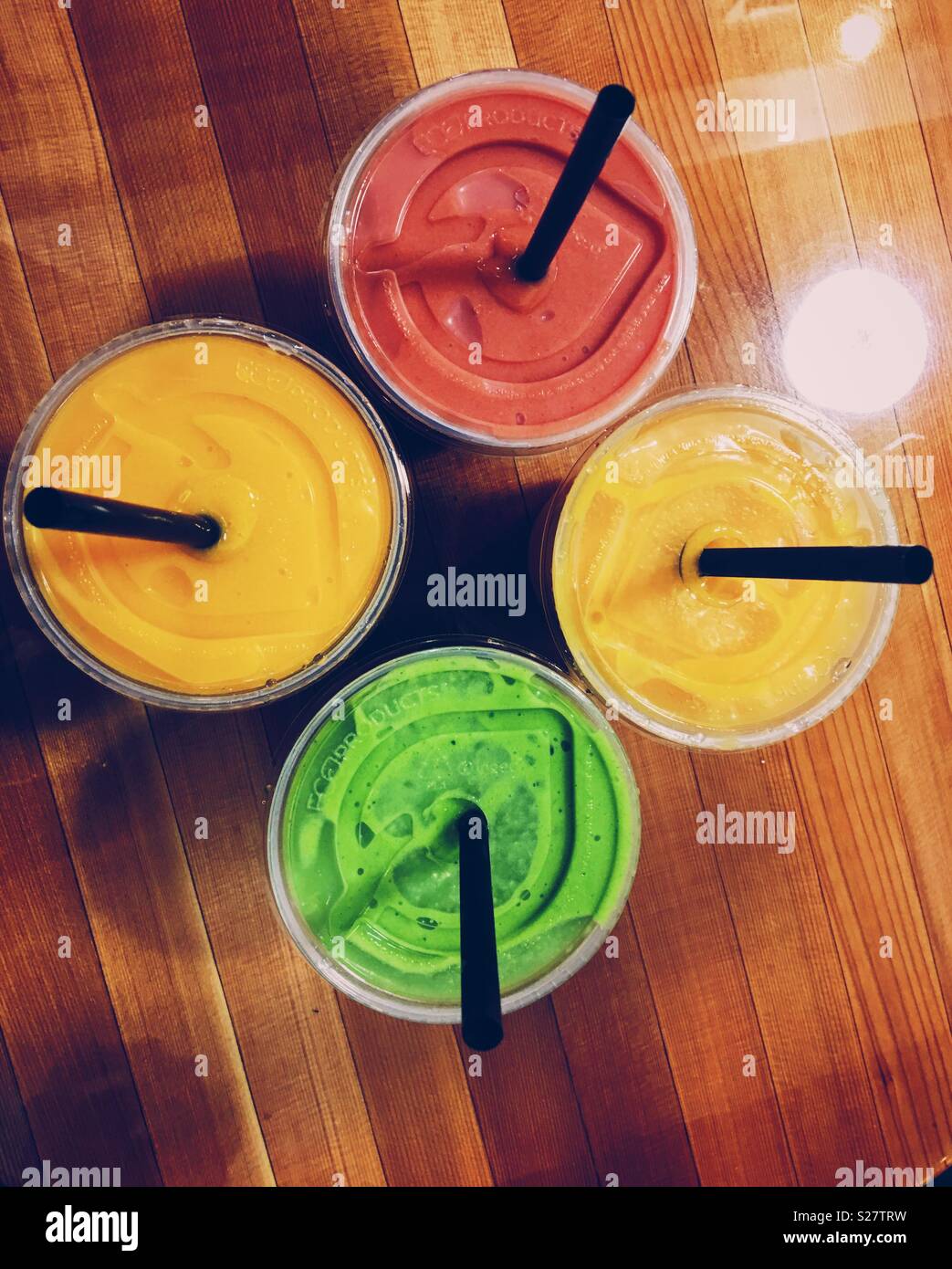 https://c8.alamy.com/comp/S27TRW/four-colourful-fruit-smoothies-in-plastic-cups-with-plastic-straws-on-a-wooden-table-photographed-from-above-S27TRW.jpg