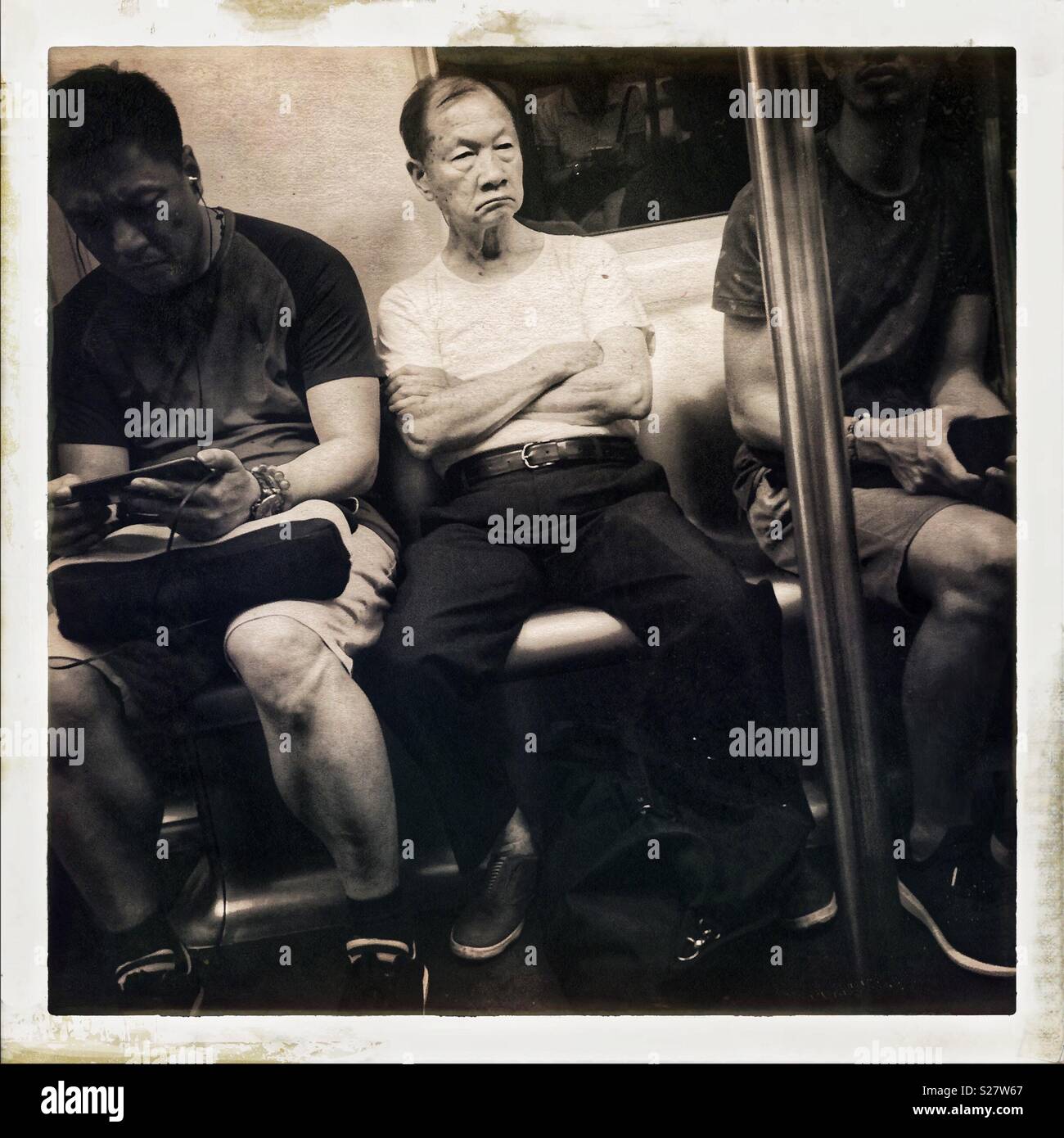 Grumpy-looking man on the MTR, Hong Kong Stock Photo
