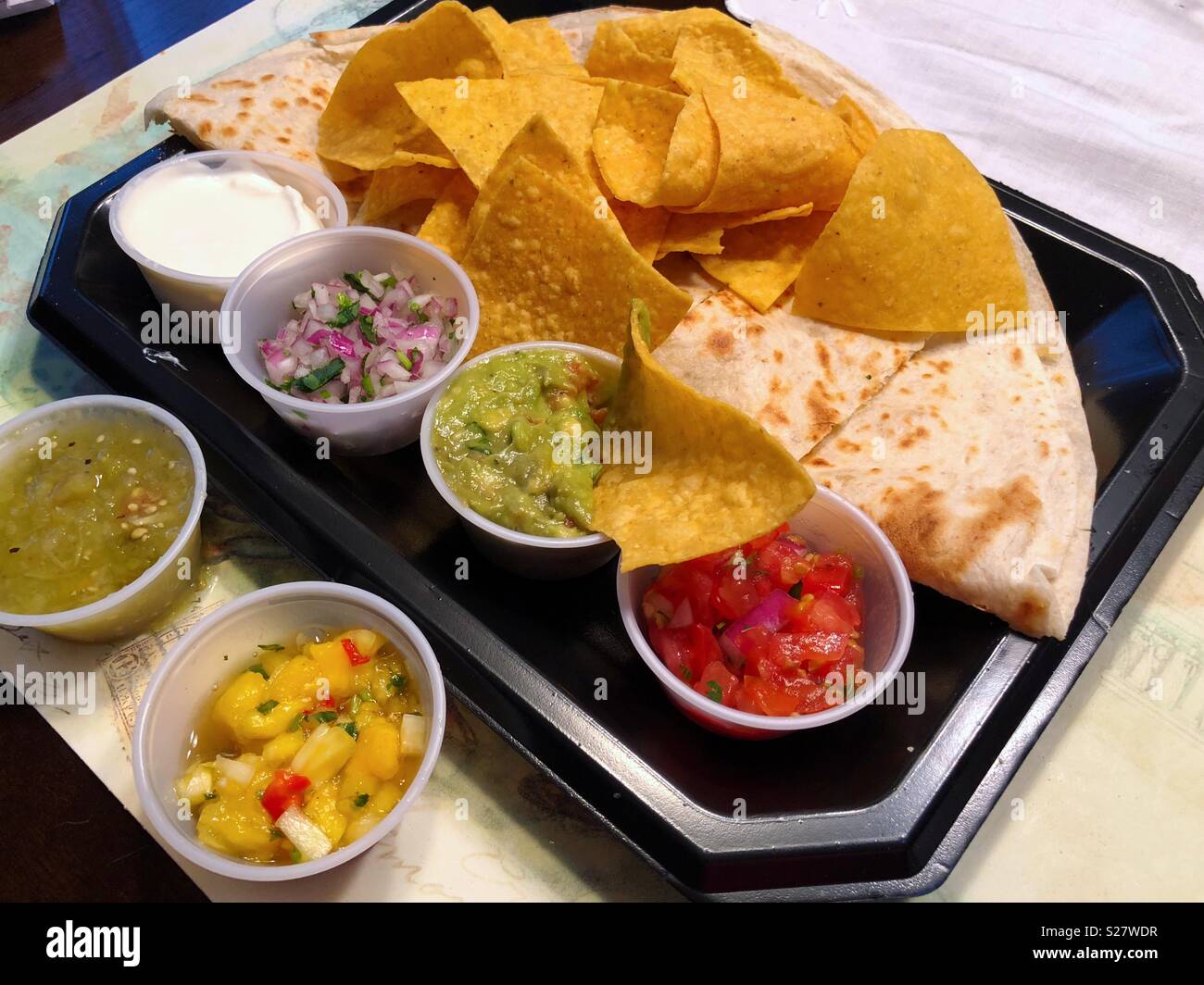 Corn chips, various salsas and a quesadilla on a plastic disposable plate Stock Photo