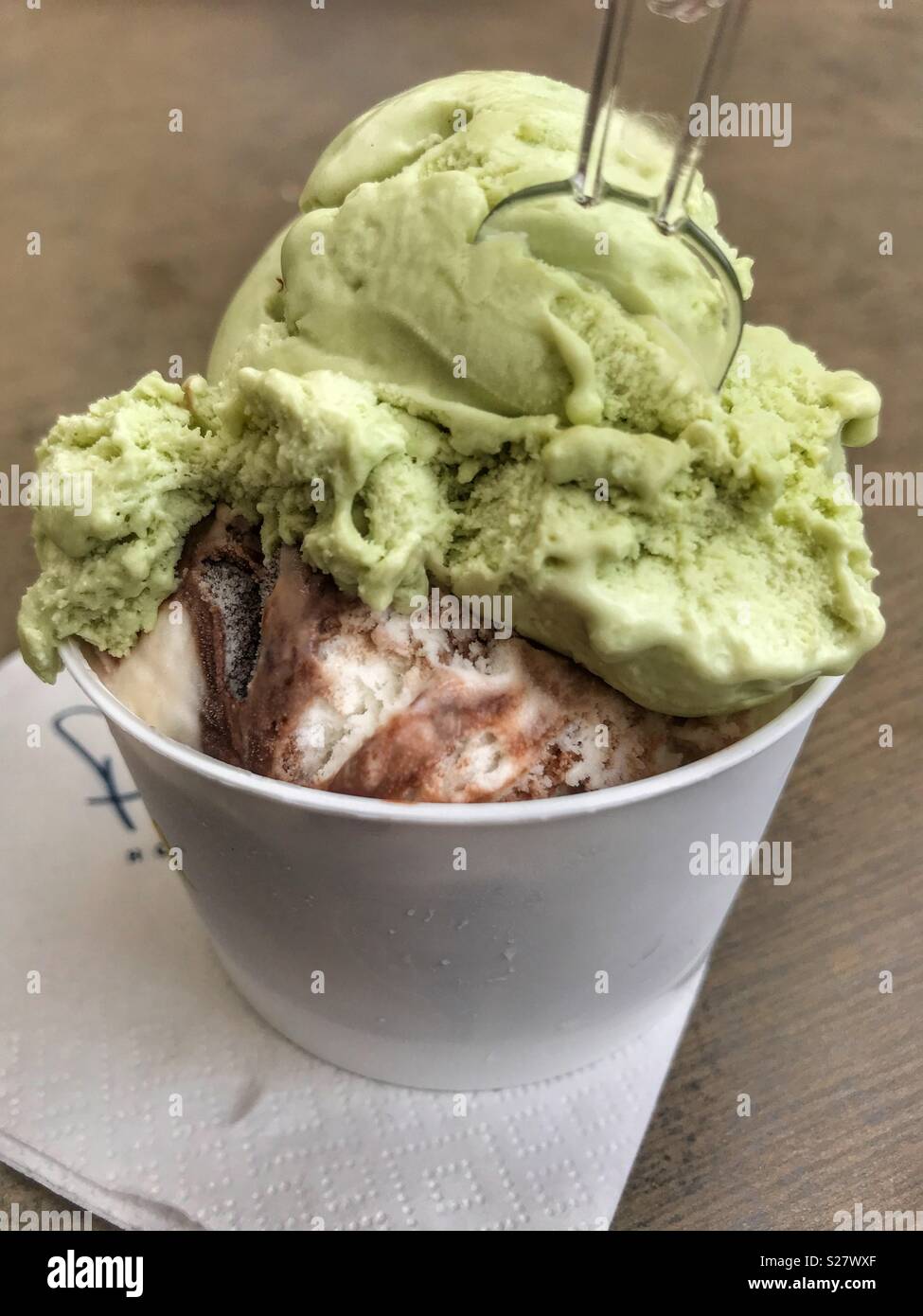 Two scoops of Ice cream in a take away plastic tub with a plastic spoon