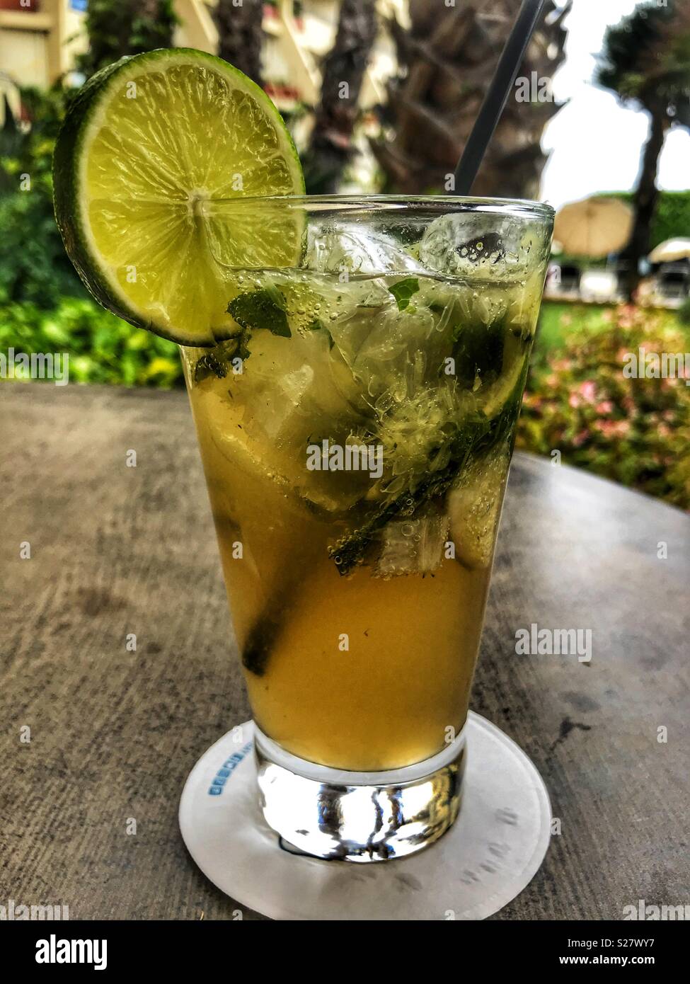 mojito cocktail with fresh lime and crushed mint in a tall glass with a plastic straw; tabletop Stock Photo