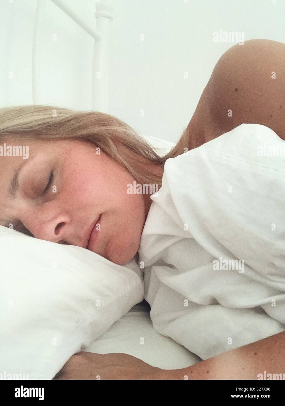 Sleeping lady in white bed sheets alone Stock Photo