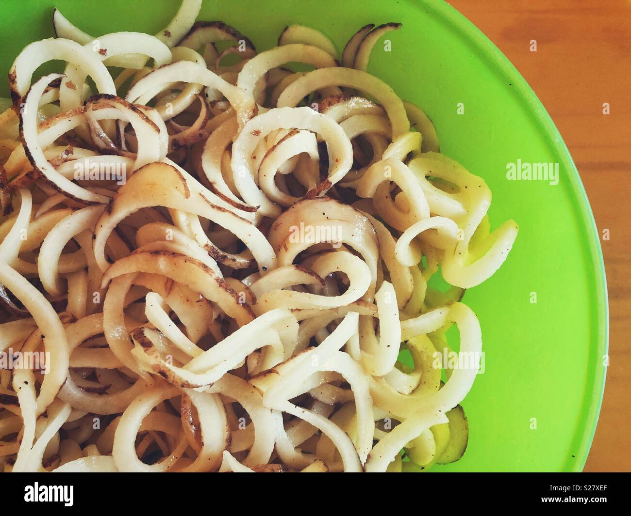Closeup of spiralized white potatoes with skins in a green plastic bowl - Smartphone Captured Stock Image