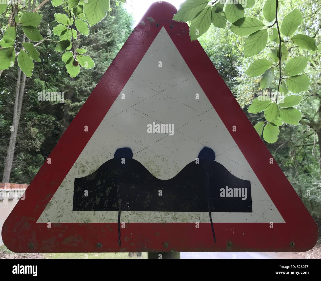 Defaced Uneven Road Sign Stock Photo