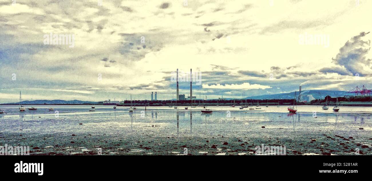 Dublin Bay viewed from the Clontarf area with the chimneys of the old Poolbeg power station in the background and small boats moored - Smartphone Captured Stock Image