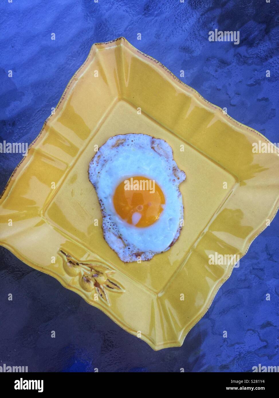 One Fried egg on yellow plate with blue background - Smartphone Captured Stock Image